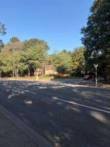 A main road junction with trees on the corner as you look at the junction.